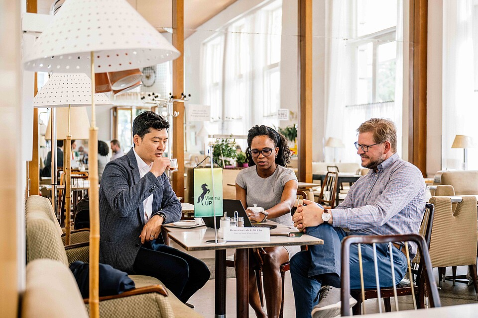 Three people sitting around a table in a Viennese coffee house during the ViennaUP festival