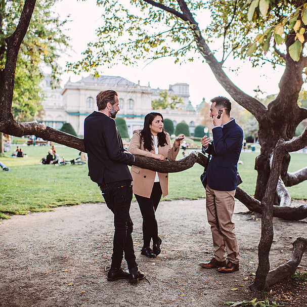 Two men and a woman standing in Stadtpark and speaking