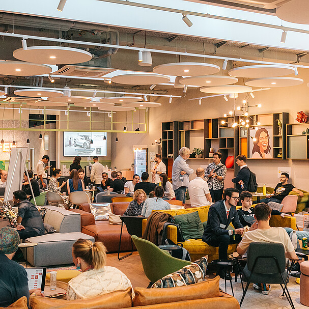 Many people in a co working space, sitting around tables